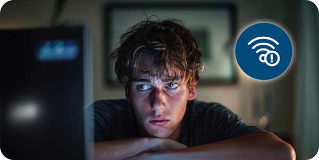 A person looking frustrated while staring at a buffering screen on their computer, symbolizing poor internet connectivity.